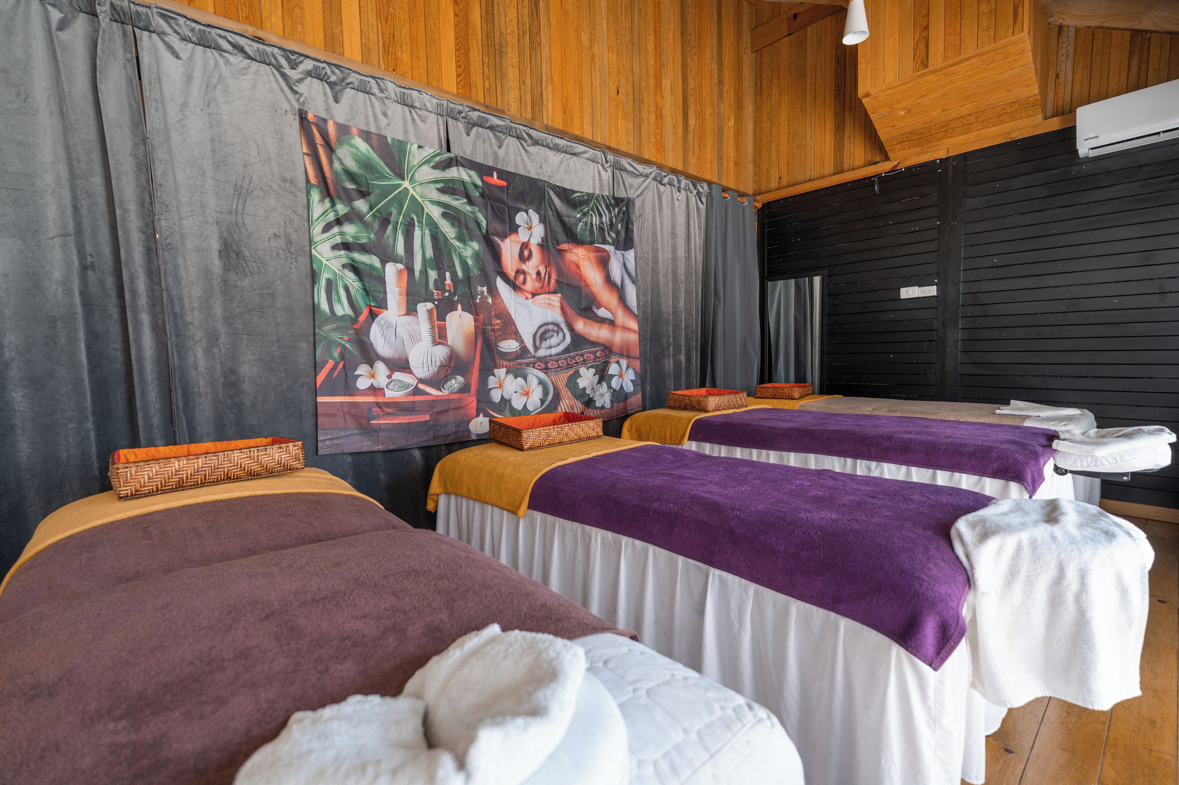 A room with massage tables, towels, and a large poster on the wall.