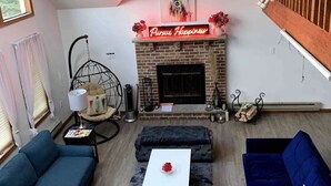 A modern living room with a fireplace, two sofas, a coffee table, and a hanging chair. - Escape to ‘Pursue Happiness’ - Your Poconos Retreat! (Tobyhanna)