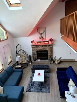 A modern living room with a fireplace, two sofas, a coffee table, and a hanging chair. - Escape to ‘Pursue Happiness’ - Your Poconos Retreat! (Tobyhanna)