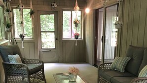 A cozy room with wicker furniture, a glass coffee table, and hanging plants. - Escape to ‘Pursue Happiness’ - Your Poconos Retreat! (Tobyhanna)