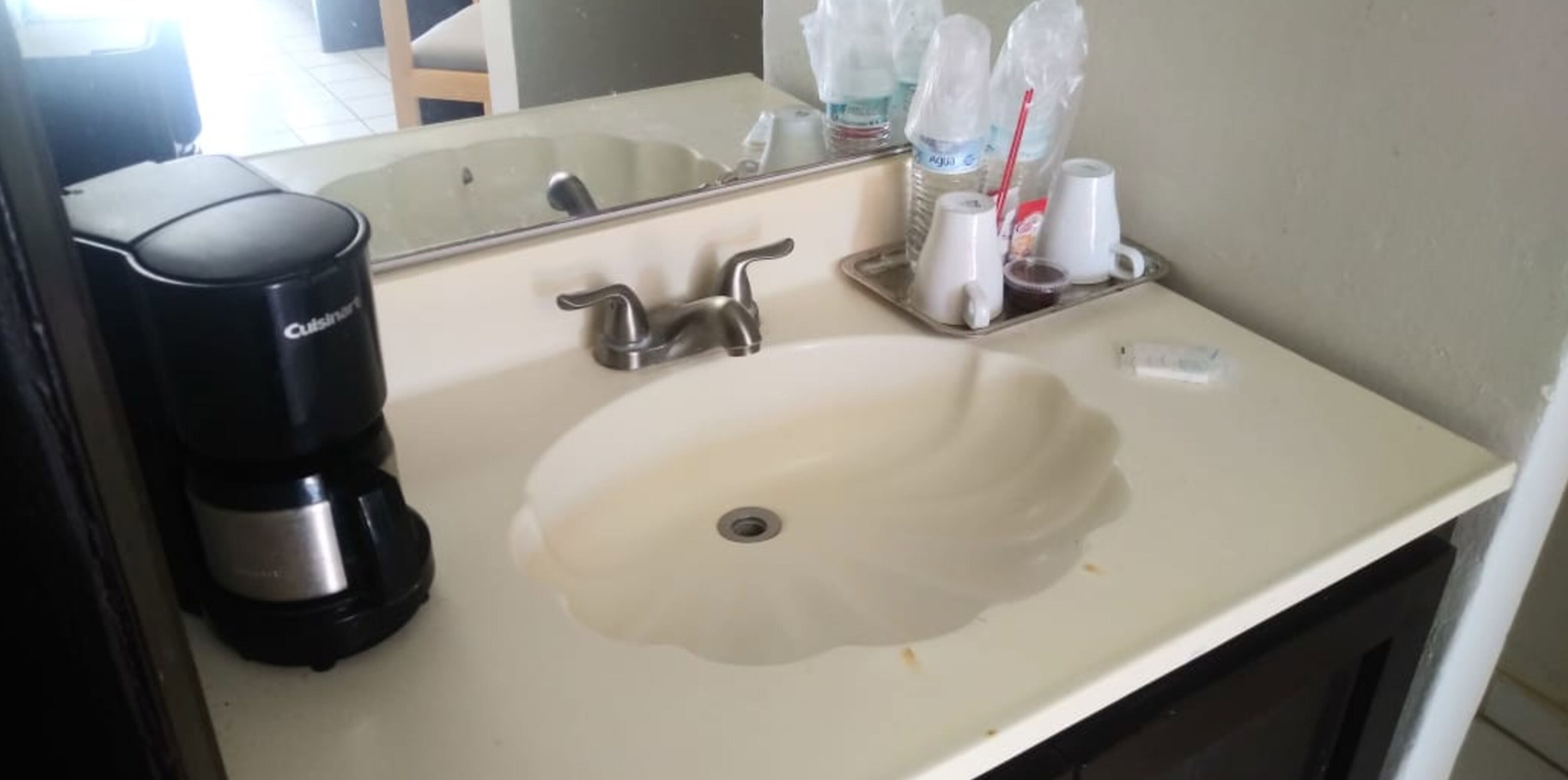 A hotel bathroom with a sink, a coffee maker, and toiletries on the counter.