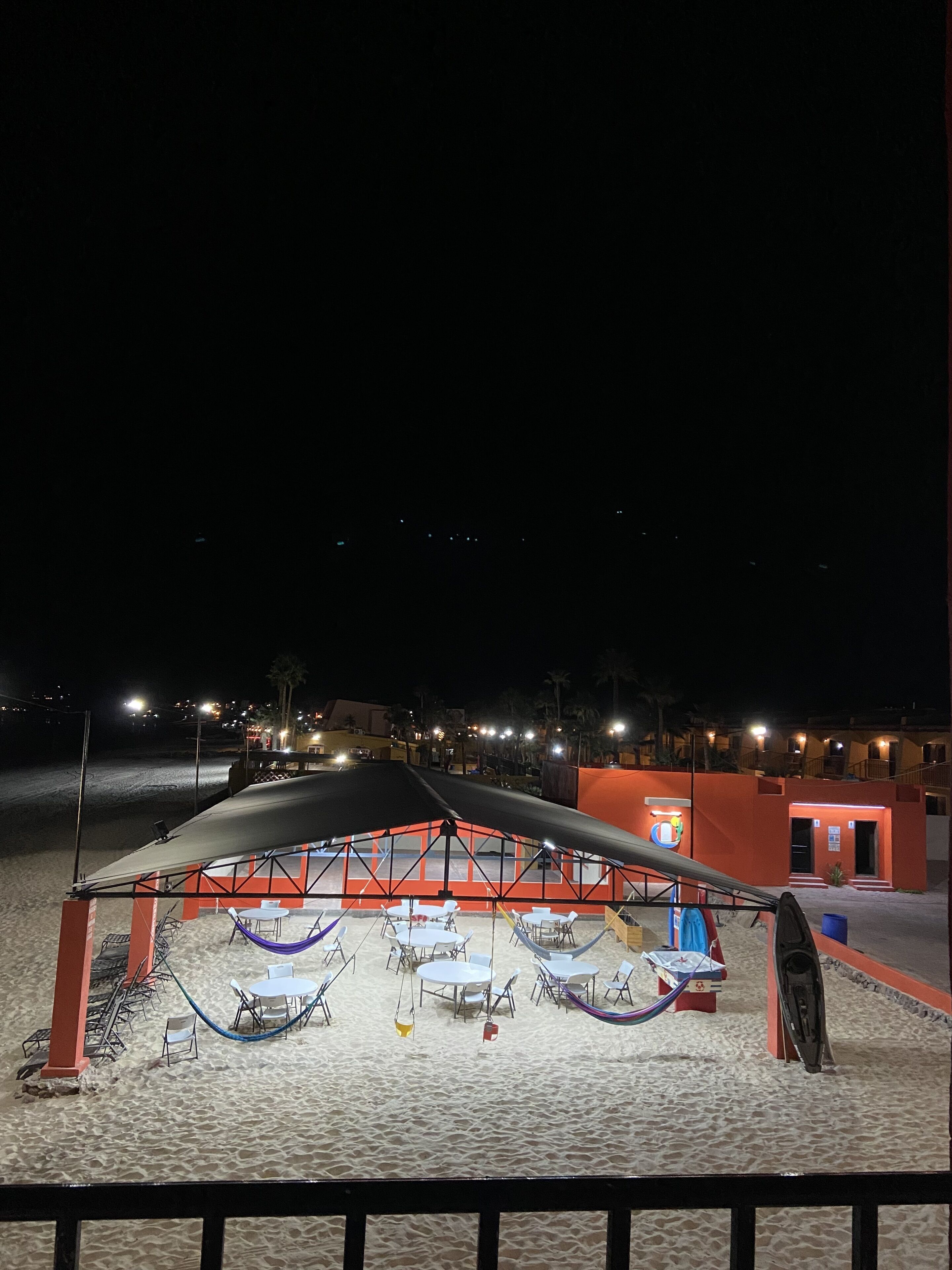 A beachside restaurant with outdoor seating and a covered area.