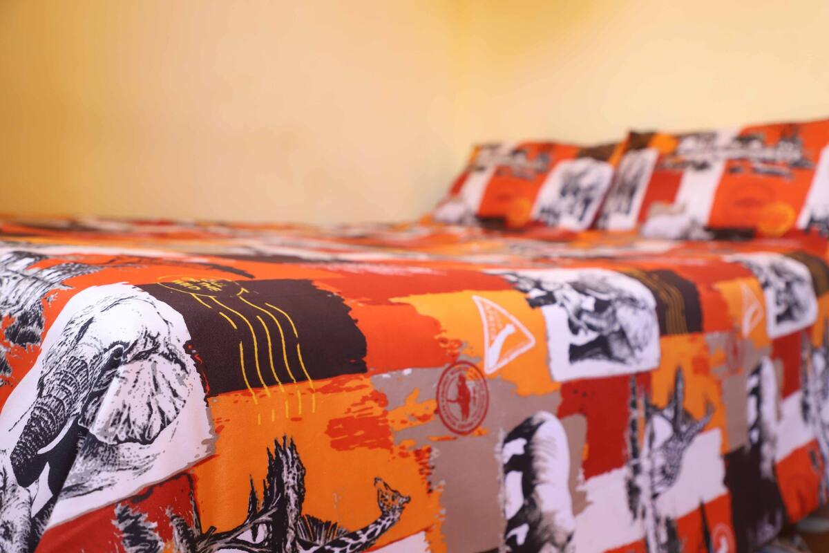 A bed with a patterned bedspread featuring various images and designs.