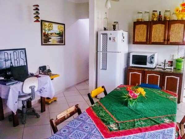 Une petite pièce agréable et chaleureuse, comprenant une table à manger, des chaises, un réfrigérateur, un four à micro-ondes, un bureau et un meuble avec des bocaux.
