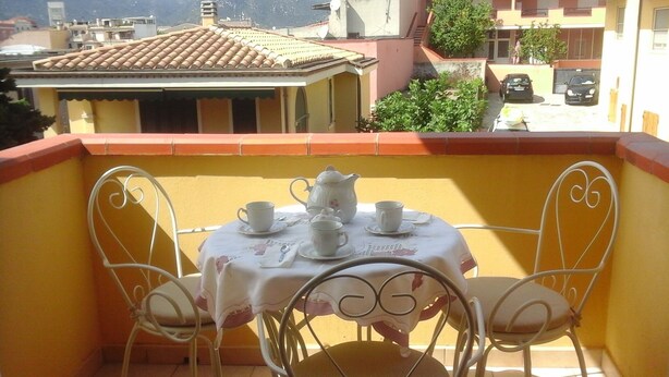 Un balcón con una mesa para dos, sillas y un mantel.