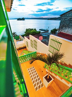 A balcony with a view of the sea, a satellite dish, and a palm tree. - Hotel Casa Turquesa (Flores)