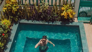 A swimming pool with a person in the water, surrounded by plants and a decorative fence. - Hotel Casa Turquesa (Flores)