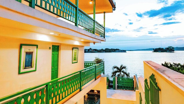 A multi-story building with green railings and a view of the water. - Hotel Casa Turquesa (Flores)