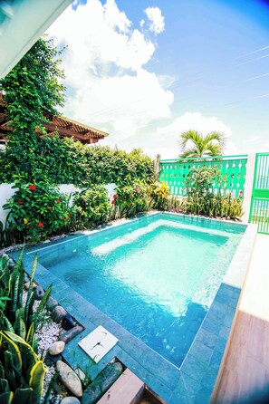 A swimming pool surrounded by lush greenery and a green fence. - Hotel Casa Turquesa (Flores)