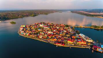 An aerial view of a coastal town with a dense cluster of colorful buildings, a marina, and a large body of water.