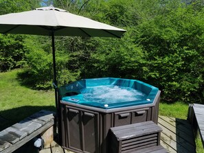 A hot tub on a wooden deck with a canopy umbrella.