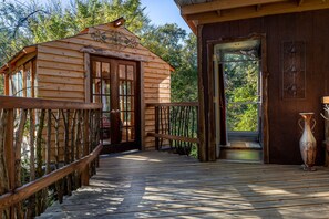 Une cabane en bois dotée d’une terrasse en bois et d’une porte vitrée donnant sur un balcon.