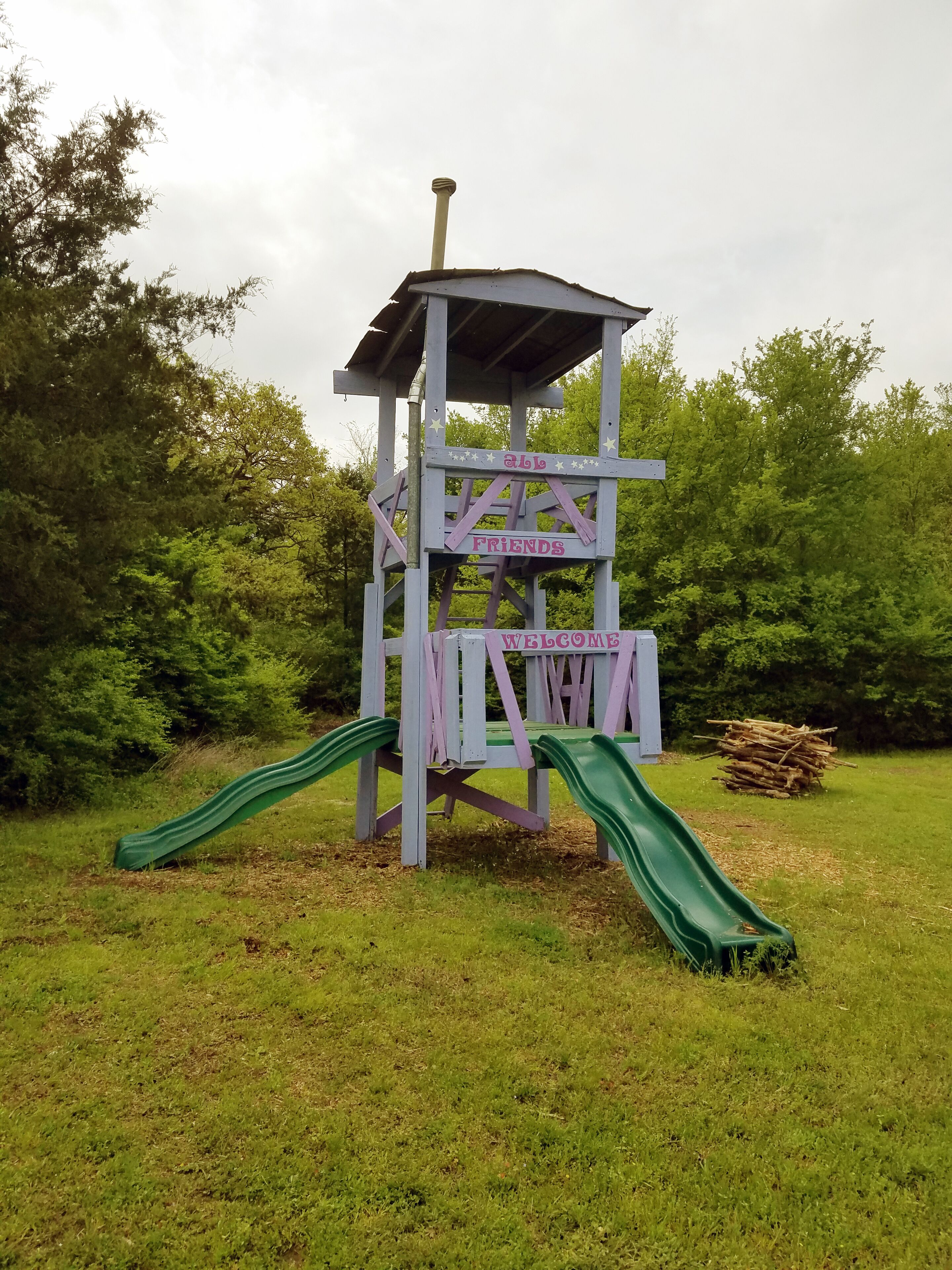 Une structure de jeux pour enfants comprenant un toboggan et une pancarte sur laquelle on peut lire : « Les amis sont les bienvenus ».