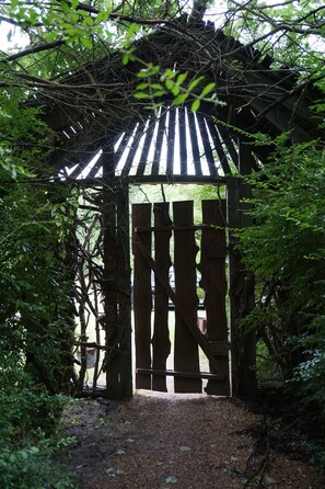 A wooden pergola structure with vertical slats and a gravel path leading to it.