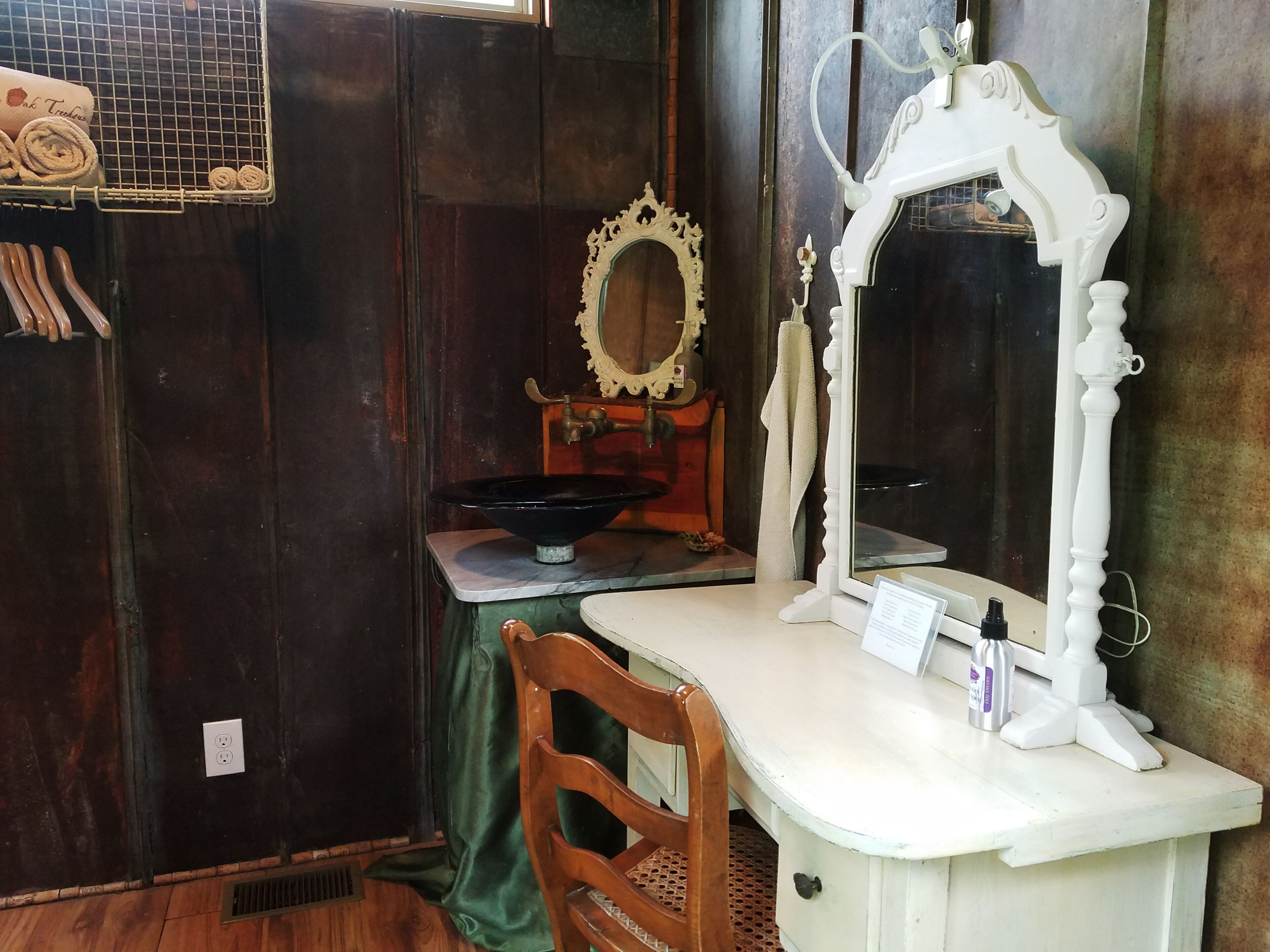 Un baño antiguo con tocador de madera, lavamanos blanco y espejo ornamentado.