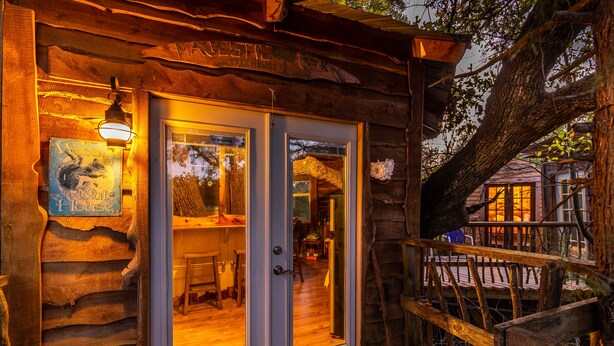 A rustic log cabin with a wooden deck and a large tree. - Savannah's Meadow (Celeste)