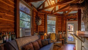 A cozy cabin interior with a wooden interior, a sofa, a table, and a bar area with bottles. - Savannah's Meadow (Celeste)