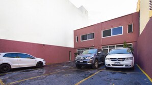 Un estacionamiento con dos coches aparcados frente a un edificio de fachada roja y blanca.