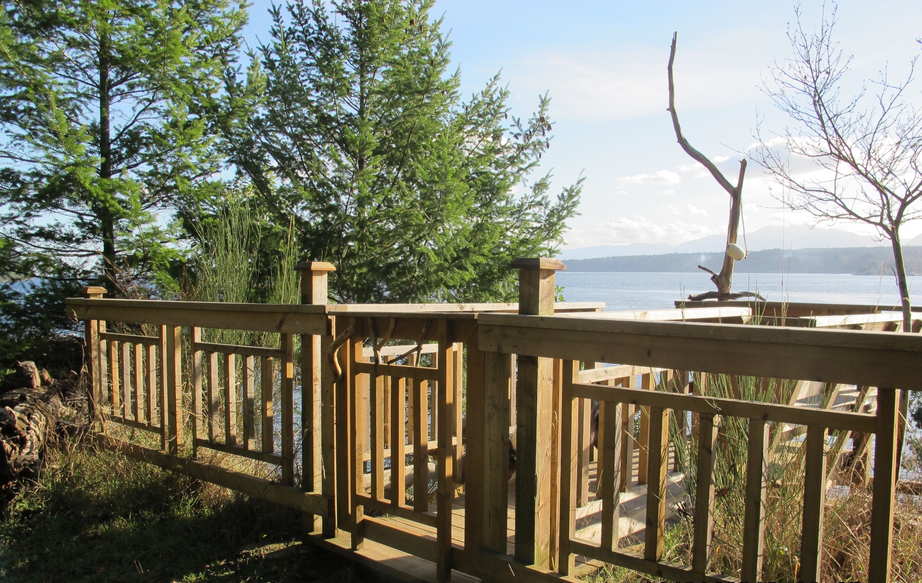 Una terraza de madera con vista a un lago y montañas a lo lejos.