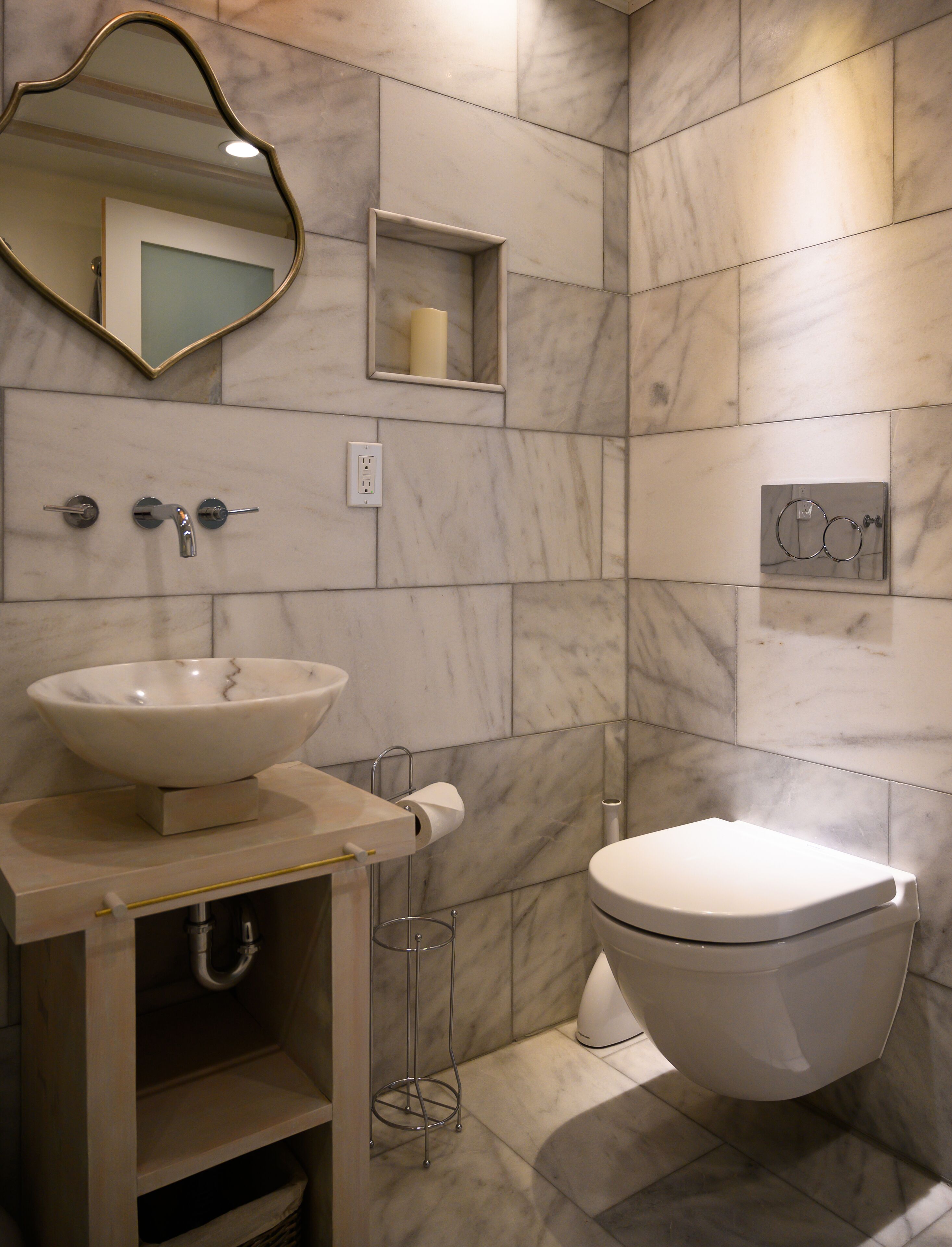 Une salle de bain moderne avec un lavabo en marbre, des toilettes et un miroir.