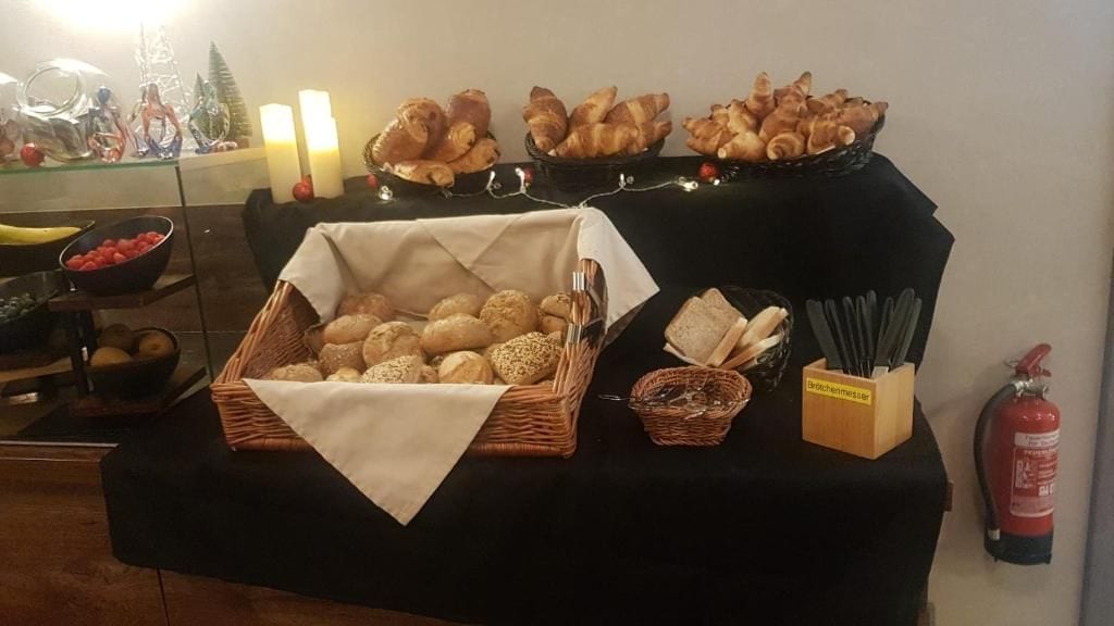 A buffet table with various breads and pastries, a fruit bowl, and a fire extinguisher.