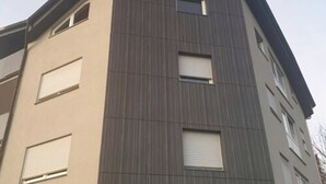 Un immeuble à plusieurs étages doté d’une architecture moderne, caractérisé par une combinaison de lignes verticales et horizontales sur la façade.
