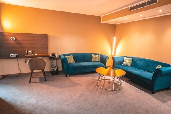 Una sala de estar moderna con un sofá azul, una mesita de centro redonda y un sillón gris.