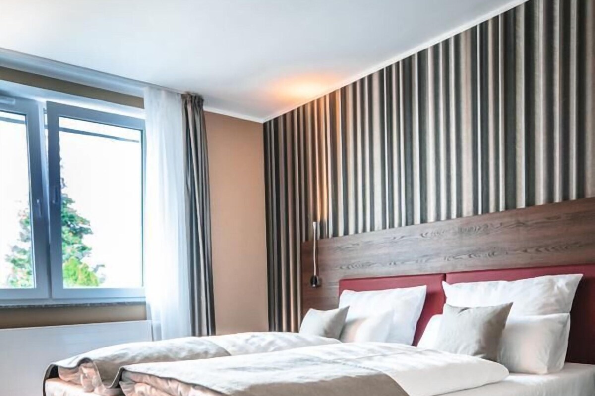 Una habitación de hotel moderna con una cama grande, vistas al exterior y un diseño de pared a rayas.
