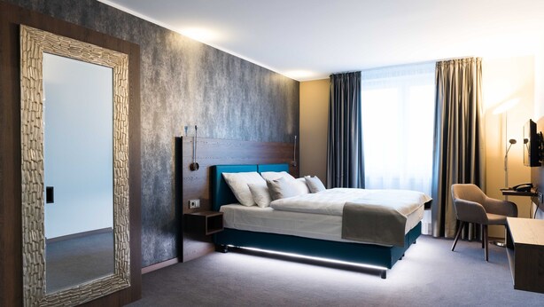 Une chambre d’hôtel moderne avec un grand lit, des tables de chevet, un bureau et une chaise.