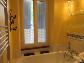 Ein Badezimmer mit Badewanne, Dusche und einer Glastrennwand.