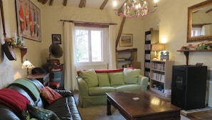 A cozy living room with a leather sofa, a green couch, a wooden coffee table, a bookshelf, and a television. - 3- Star small town cutie on the Charente River (Bourg-Charente)