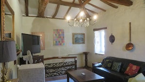 A cozy living room with a wooden ceiling, a television, a sofa, and a fireplace. - 3- Star small town cutie on the Charente River (Bourg-Charente)