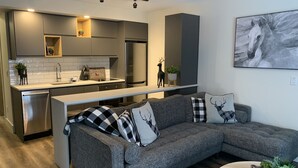 Een moderne keuken met een vast kookeiland, grijze kastjes en roestvrijstalen apparatuur.