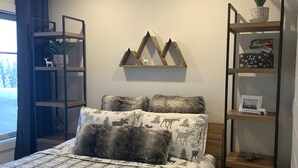 Een slaapkamer met een bed, een wandplank met decoratieve objecten, en een raam met gordijnen.