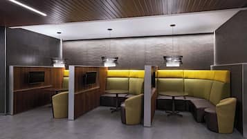 A modern, well-lit lounge area with wooden paneling, built-in seating, and pendant lighting.
