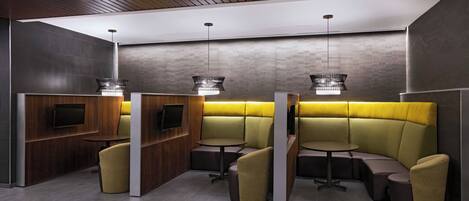 A modern, well-lit lounge area with wooden paneling, built-in seating, and pendant lighting.
