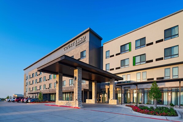 A Courtyard by Marriott hotel with a modern design, featuring a covered entrance, multiple floors, and a parking lot. - Courtyard by Marriott Dallas Grand Prairie (Grand Prairie)