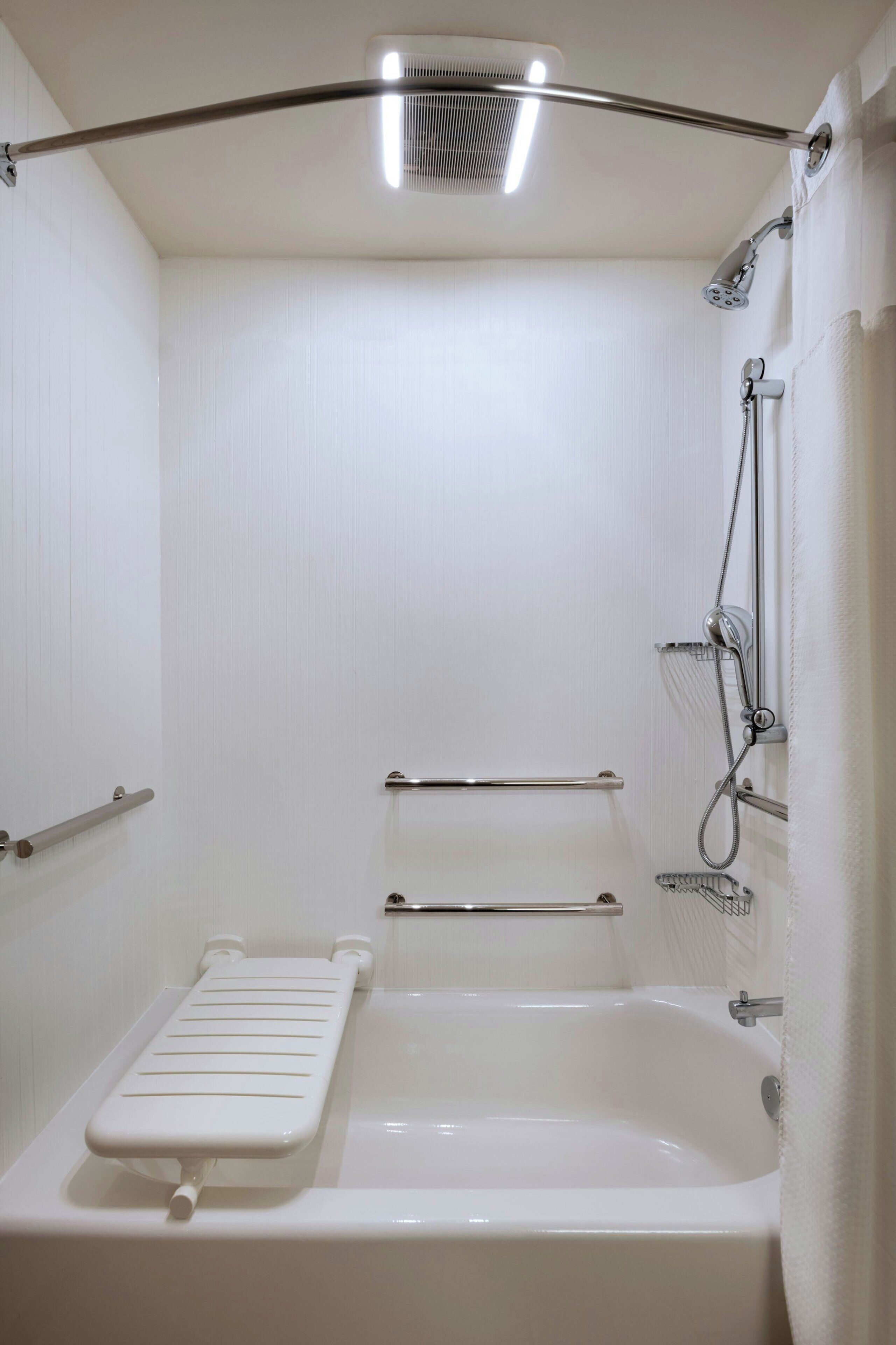 A white bathroom with a bathtub, a showerhead, and a towel rack.