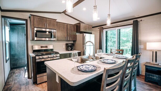 Una cocina moderna con electrodomésticos de acero inoxidable, una isla central y un comedor con vistas al exterior.