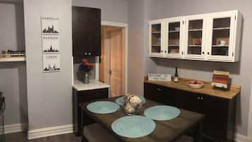 Un comedor con una mesa de madera, individuales azules y un jarrón de flores. Se observan armarios oscuros y un letrero que dice "Welcome to Oak Park".