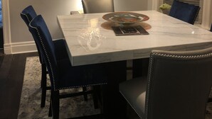A dining area with a marble table, dark upholstered chairs, a pendant light, and a framed artwork on the wall. - Cozy, Comfortable and Convenient apartment. Close to everything! (Oak Park)