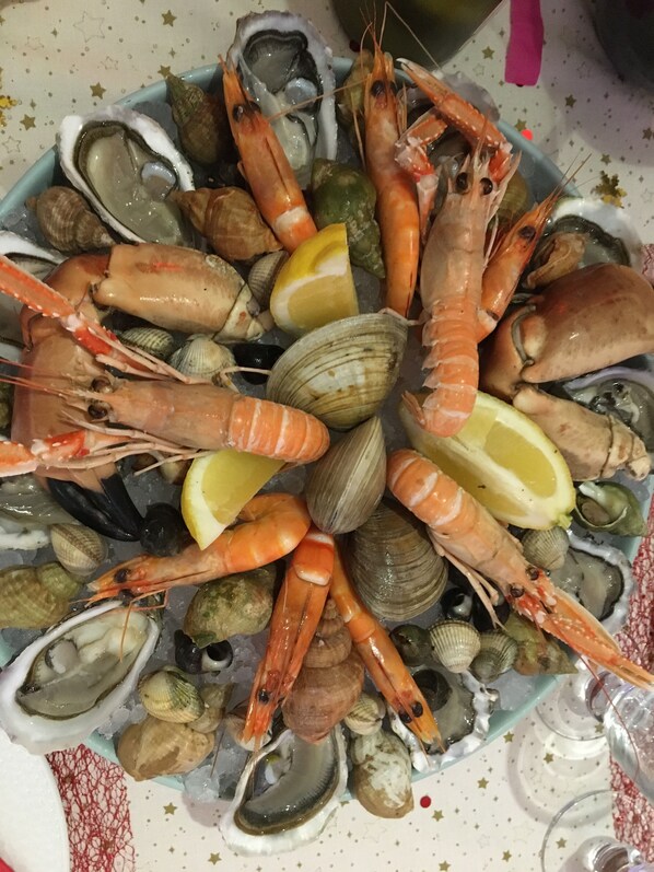 Una bandeja de mariscos con camarones, almejas y ostras sobre un plato.