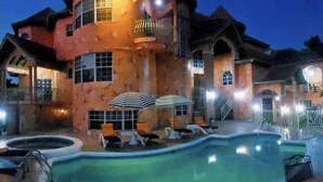 Un edificio amplio de varios niveles con piscina, zona de estar exterior y un balcón bien iluminado.