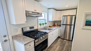 A modern kitchen with white cabinets, stainless steel appliances, granite countertops, and a wooden floor. - Great Blue Resorts - McCreary's Beach (Drummond-North Elmsley)