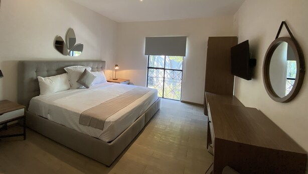 Un dormitorio moderno con una cama grande, mesitas de noche, televisión y ventana con vistas.