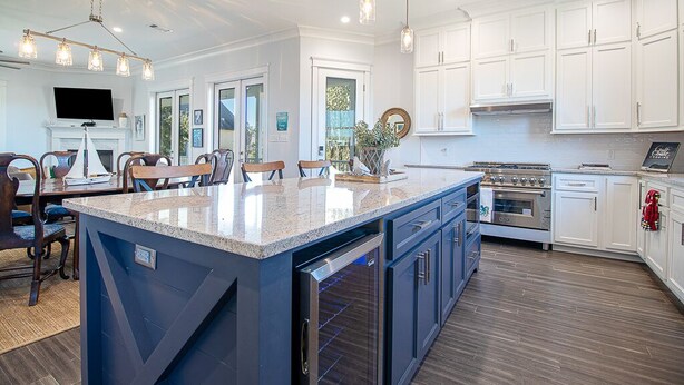 A modern kitchen with a large island, white cabinets, stainless steel appliances, and pendant lighting. - EXPANSIVE PORCH-Gulf Breezes-Beach Views & Gorgeous Oak tree (Pass Christian)