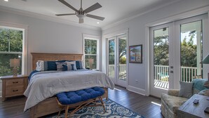 A bedroom with a large bed, a ceiling fan, and a view of the outdoors through large sliding glass doors. - EXPANSIVE PORCH-Gulf Breezes-Beach Views & Gorgeous Oak tree (Pass Christian)