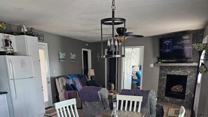 Uma cozinha moderna com armários brancos, uma mesa de jantar com cadeiras brancas e uma lareira.