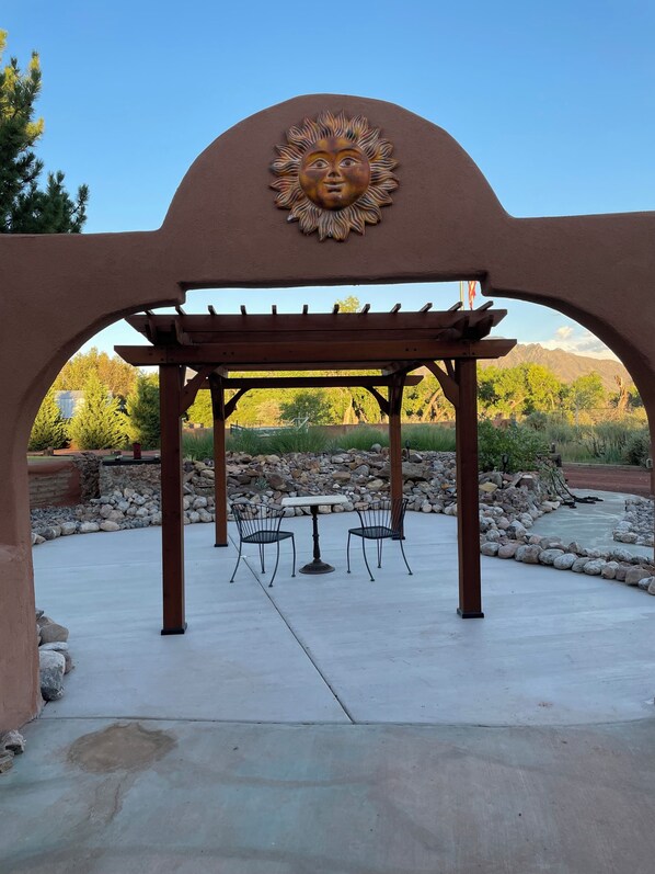 A covered patio area with a pergola, two chairs, and a table. - Tierra de Milagros~ Peaceful ~ Private ~ Secure (Bernalillo)