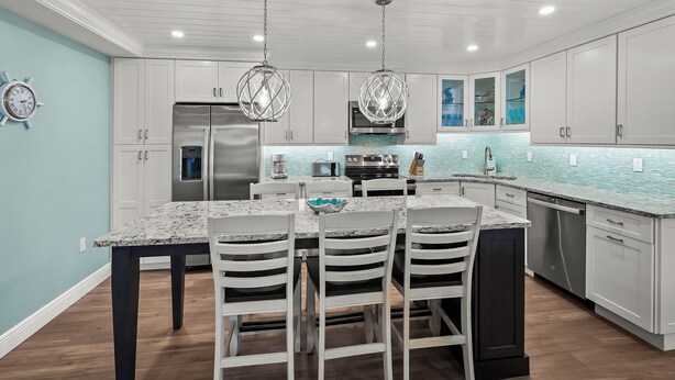A modern kitchen with white cabinetry, a granite countertop, and a central island with four chairs. - Newly Renovated Dock View 2 bed, 2 bath at Sanibel Moorings #1641 (Sanibel)